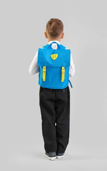 Mały Uczeń Niebieskim Plecakiem Szarym Tle Widok Tyłu — Zdjęcie stockowe