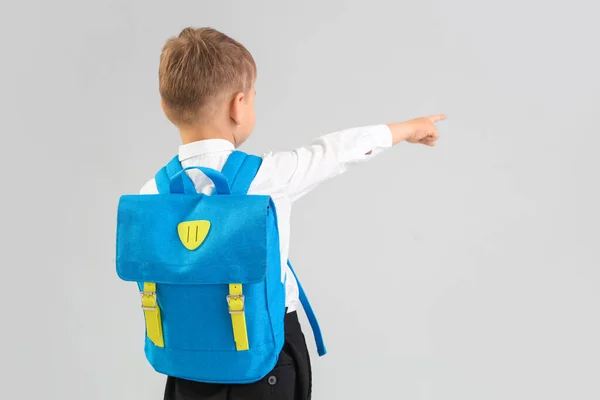 小男孩 蓝色背包指着灰色背景的东西 后视镜 — 图库照片