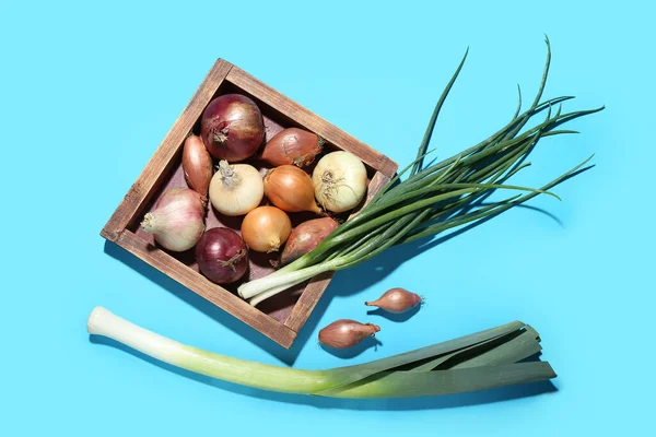 stock image Wooden board with different kinds of onion on blue background