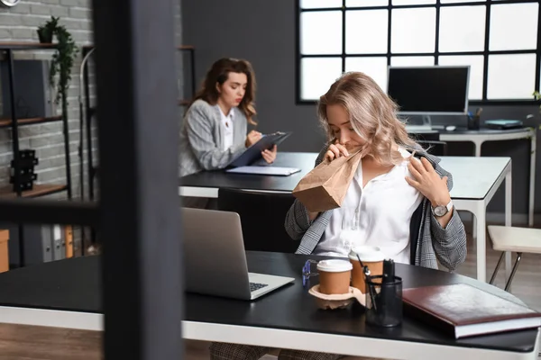 stock image Young woman with paper bag having panic attack in office