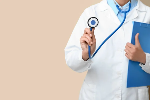 Ärztin Mit Stethoskop Und Klemmbrett Auf Beigem Hintergrund — Stockfoto
