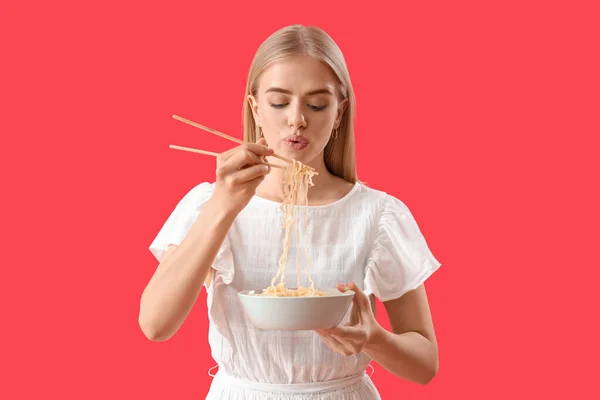 Junge Frau Isst Nudeln Auf Rotem Hintergrund — Stockfoto