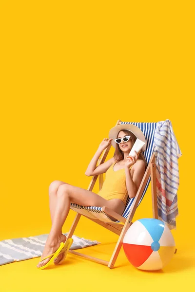 Young Woman Sunscreen Cream Sitting Deck Chair Yellow Background — Stock Photo, Image