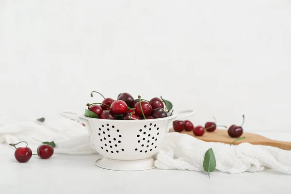 stock image Colander and board with sweet cherries on white background