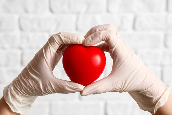 stock image Doctor with plastic heart on white brick background