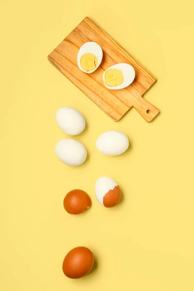 stock image Tasty boiled eggs and wooden board with halves on yellow background