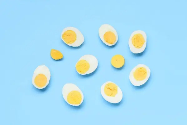 stock image Halves of tasty boiled eggs on blue background