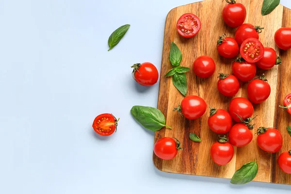 Drewniana Deska Świeżymi Pomidorami Wiśniowymi Bazylią Niebieskim Tle — Zdjęcie stockowe