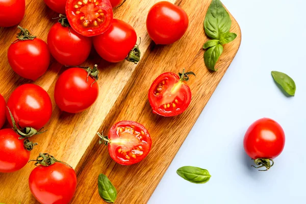 Drewniana Deska Świeżymi Pomidorami Wiśniowymi Bazylią Niebieskim Tle — Zdjęcie stockowe