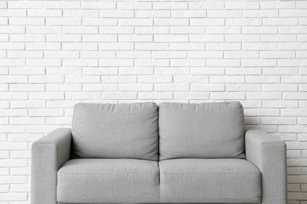 Przytulna Szara Sofa Pobliżu Ściany Białej Cegły — Zdjęcie stockowe