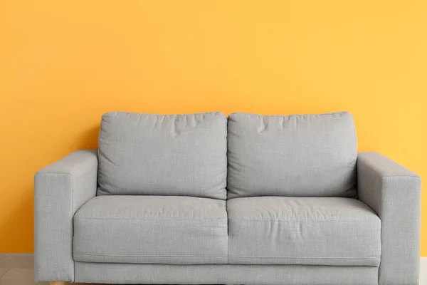 オレンジの壁の近くの居心地の良い灰色のソファ — ストック写真