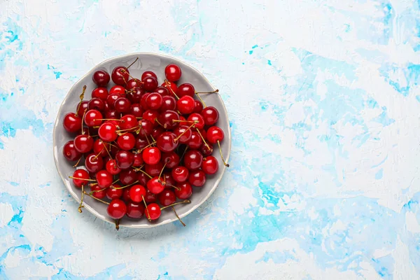 stock image Plate with red sweet cherries on light blue background