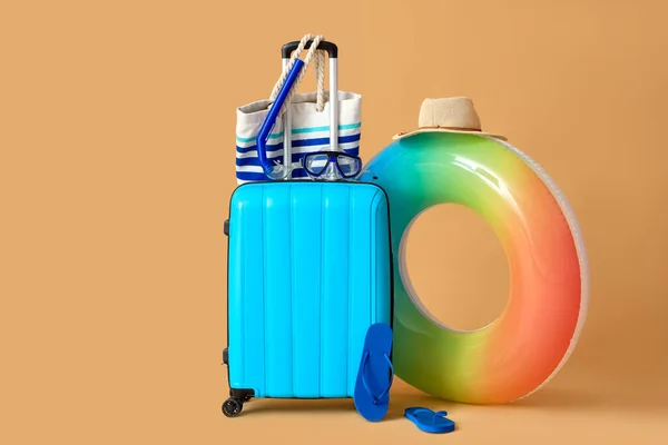 stock image Suitcase with inflatable ring and beach accessories on beige background. Travel concept