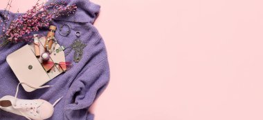 Pembe arka planda çantalı ve aksesuarlı şık bayan süveteri ve metin için yeri var.