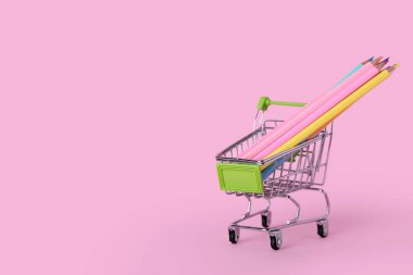 Pembe arka planda kalemleri olan alışveriş arabası.