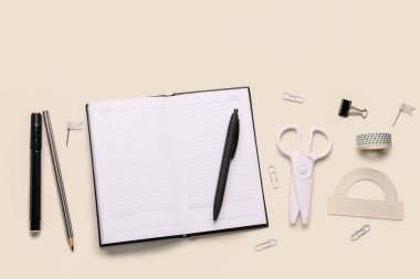 Işık arkaplanı üzerinde boş bir defter olan farklı kırtasiye seti