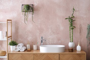 Masada bambu saplı lavabo, banyo aksesuarları ve vazo var.