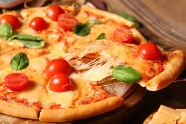 Ahşap masada lezzetli bir pizza margaritası ve fırın kağıdı.