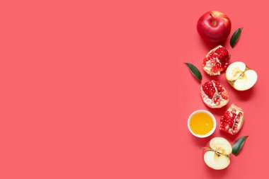 Kırmızı zemin üzerinde olgun elmalar, nar ve bal olan kompozisyon. Rosh hashanah (Yahudi Yeni Yılı) kutlaması