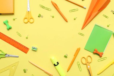 Kağıt uçaktan yapılmış çerçeve ve sarı arka planda farklı okul kırtasiyesinden