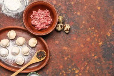 Pişmemiş hamur köfteleri ve grunge arkaplanındaki malzemelerle dolu tabak.