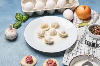 Pişmemiş hamur köfteleri ve mavi arka plandaki malzemelerle dolu bir tabak.