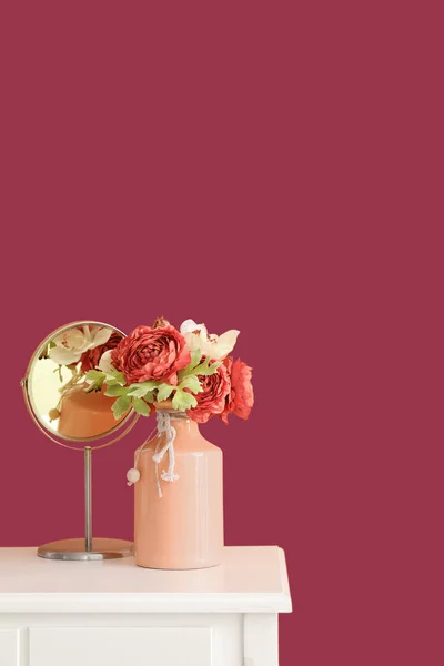 在粉红墙边的桌子上挂上花朵和镜子 — 图库照片