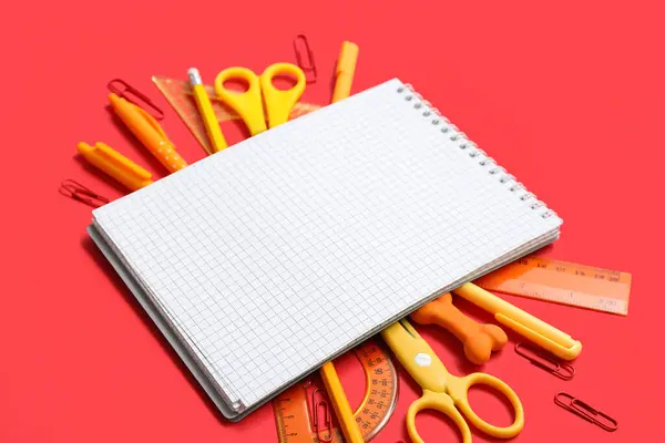 带有空白笔记本和红色背景的学校文具的作文 — 图库照片