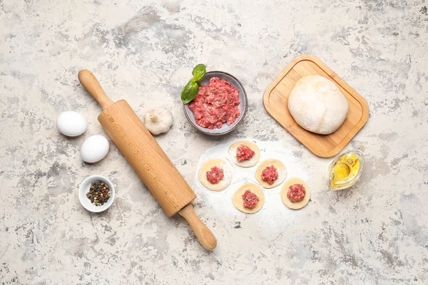 Stock image Raw dough with minced meat and ingredients for preparing dumplings on beige background