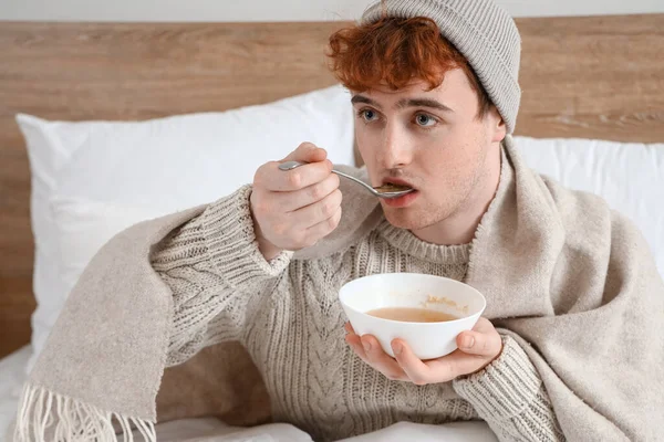 若い男食べるスープでベッドルーム — ストック写真