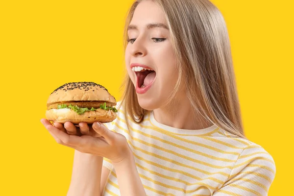 Junge Frau Mit Leckerem Burger Auf Gelbem Hintergrund Nahaufnahme — Stockfoto