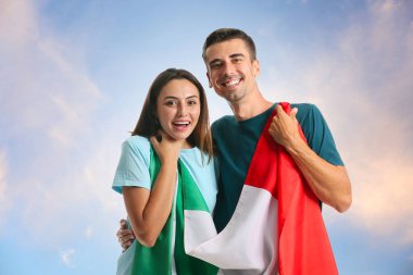 Mavi gökyüzüne karşı İtalyan bayrağı taşıyan genç çift