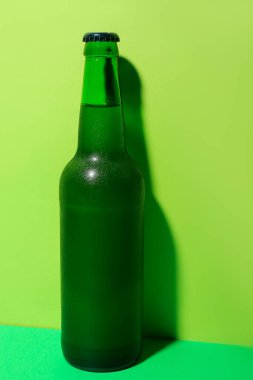 Yeşil arka planda bir şişe soğuk bira.