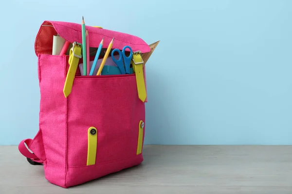 ピンクの学校のバックパックにはさみ ノート 鉛筆が青い壁の近くの灰色の木製のテーブルに — ストック写真
