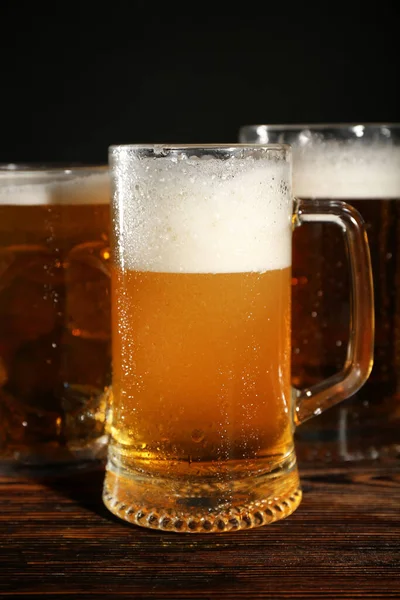 stock image Mugs of cold beer on wooden table, closeup