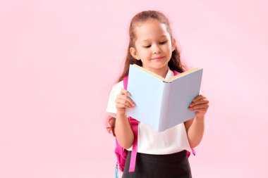 Pembe arka plan kitabı olan küçük bir kız öğrenci.