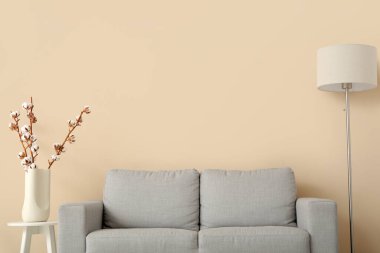 Oturma odasının içinde kanepe, lamba ve pamuklu dallar var.