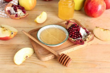 Tahta masada, Rosh Hashanah kutlaması (Yahudi Yeni Yılı) için bir kase bal, nar ve elmayla birlikte.