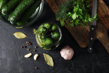 Kavanoz ve kase, siyah arka planda korunması için taze salatalıkla birlikte.