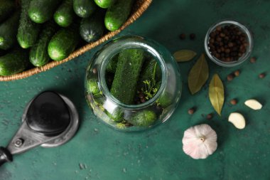 Yeşil arka planda tutmak için taze salatalıklı kavanoz.