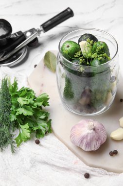 Beyaz mermer arka planda korunması için taze salatalıklı kavanoz.