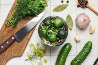 Taze salatalıklı kavanoz ve beyaz fayansların korunması için gerekli malzemeler.