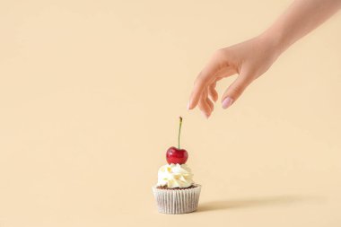 Lezzetli çörekleri bej arka planda kirazla süsleyen kadın.