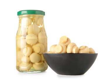 Beyaz arka planda konserve mantarlı kavanoz ve kase.