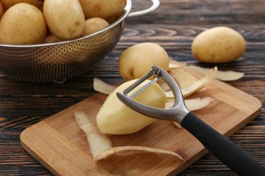 Tahta arka planda çiğ patatesli kevgir ve yemek.