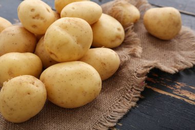 Siyah ahşap zeminde bir sürü çiğ patates, yakın plan.