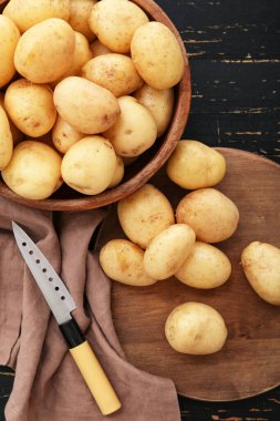 Siyah ahşap arka planda çiğ patatesli yemek ve kase.