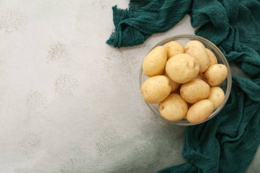 Beyaz arka planda çiğ patatesli cam kase.