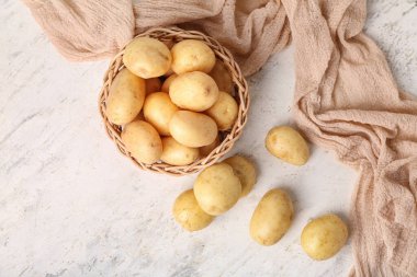 Beyaz masada çiğ patatesli hasır kase.