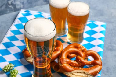 Bavyera bayrağı, biralı kupalar ve mavi arka planda krakerler.